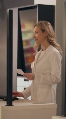 Kadın eczacı sağlık görevlisi, eczaneden ilaç alan müşterilere danışmanlık yapıyor. Yaşlı adam ilaç sipariş ediyor. Ağrı kesiciler alıyor.