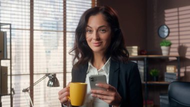 Kafkasyalı bir kadın elinde kahve, cep telefonu, akıllı telefon, gülücük, kadın, iş kadını, internet, kayan işveren müdürü sosyal medya çay molası veriyor.