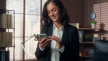 Kafkasyalı mutlu bir kadın elinde cep telefonuyla gülümsüyor akıllı telefonlu kız internet cihaz yöneticisi iş kadını iş kadını ofis çalışanı sosyal medya interneti