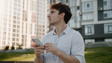 Düşünceli Kafkasyalı adam cep telefonu kullanıyor. Akıllı adam düşünüyor. GPS navigatörüne bakıyor. Çevrimiçi erkek işadamı iş dünyası açık hava çözümleri işveren sorunu.