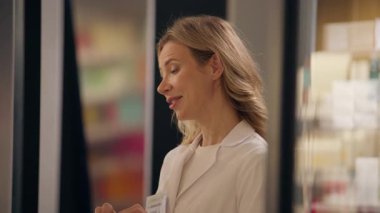 Eczacı kadın gülümseyen kadın ilaç paketi alırken müşteriye yardım ediyor. İlaç hapı alıyor, vitamin alıyor, ilaç tedavisi görüyor, ilaç tedavisi görüyor eczaneden sağlık hizmeti satın alıyor.