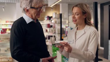 Eczaneden kalp ilacı alan yaşlı bir müşteri. Kadın eczacı. Hasta bakıcısı.
