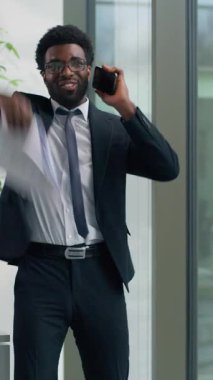 Öfkeli Afrikalı Amerikalı işadamı cep telefonuyla bağırıyor modern ofis işadamı hayal kırıklığına uğramış evrakları fırlatıyor pencereden dışarı bakıyor erkek yönetici stresli çatışma çağrısını bastırıyor