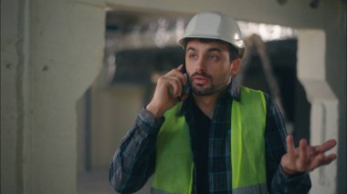 Sinirli Kafkasyalı mimar cep telefonuyla konuşuyor inşaat ustabaşısı elektrikçi erkek haberleşen akıllı telefon müfettişi tamirci sorununu tartışıyor.