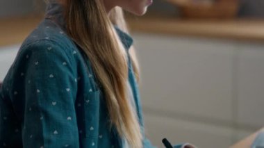 Beyaz kız liseli kız öğrenci kız öğrenci öğrenci çalışması. Ev mutfağında notlar yazıyor. Uzaktan öğretmenle e-öğreniyor.