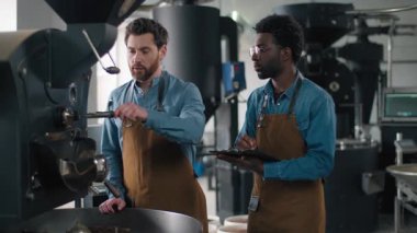 İki farklı Afrikalı Kafkasyalı adam kavrulmuş kahve aromasını inceliyor. Kontrol listesi yazıyorlar. Kalite kontrol rostoyu kokluyorlar.