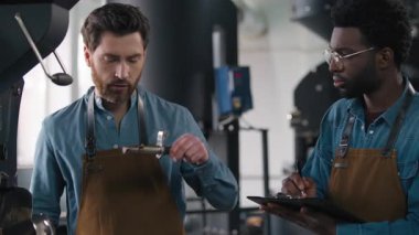 İki farklı kahve fabrikası çalışanı aroma testi belgelerini inceliyor. Sonuçları kızartıyorlar. Afrikalı Amerikalı kahveci, kahve listesindeki Kafkasyalı meslektaşı, fasulye aromalı ve hassas espresso kalitesinde oturum değerlendirmesini yapıyor.