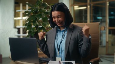 Mutlu Asyalı Çinli Japon iş kadını bilgisayar ekranında çalışırken zafer kazanmanın keyfini çıkarın. Başarılı iş kadını, kadın işveren, dans eden bayram menajerini kutluyor.