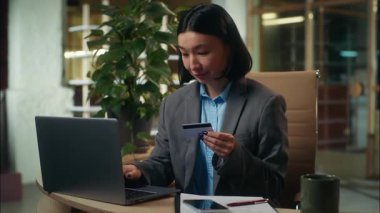 Mutlu Asyalı Koreli Çinli kadın internetten alışveriş yapıyor. Laptop ile alışveriş yapıyor. Kredi kartı işkadını.