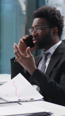 Kafası karışmış Afrikalı Amerikalı bir adamın cep telefonu işadamı cep telefonu iş telefonu görünen bilgisayar monitörü, bilgisayar çalışanı yönetici sorun sorunu, ofis müşterisine danışmanlık yapan kafası karışık bir adam.