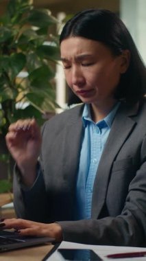 Yorgun, fazla çalışan Asyalı kadın baş ağrısı, baş ağrısı, kadın iş kadını migren ağrısı, ofis işi, dizüstü bilgisayar yorgunluğu, aşırı yorgunluk, kadın işveren stresi.