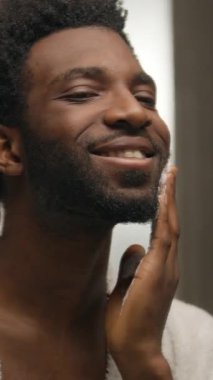 Aynanın yansıması, sakalını tıraş eden Afrikalı Amerikalı adam banyoda köpüklü jel sürüyor gülümseyen sakallı adam, erkek, lekeli, sakallı, kıllı, kıllı, cilde dokunan, cilt bakımını yapan, yüz estetiğine hazırlanıyor.