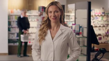 Gülümseyen Kafkasyalı kadın doktor çocuk doktoru terapist kadın stajyer sağlık danışmanı beyaz önlüklü eczane hekimi kamera sağlık hizmeti eczanesi portresine bakıyor.