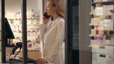 Eczane Kafkasyalı eczacı kadın cep telefonundan konuşuyor ilaç envanterini kontrol et sağlık ürünleri, vitamin ürünleri profesyonel tıbbi konsültasyon cep telefonuyla konuş