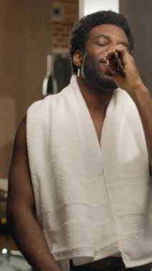 Afro-Amerikalı komik adam saç fırçasıyla ev tuvaletinde şarkı söylüyor çıplak adam pişiyor aynaya bakıyor duş alıyor etnik erkek dinleniyor dans ediyor şarkı söylüyor sağlıklı adam müzik dinliyor saç bakımını