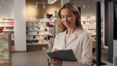 Gülümseyen kadın eczacı Kafkasyalı pratisyen doktor eczane eczanesindeki ilaç envanterini belgeledi.