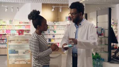 Eczacıdan konuşan bir müşteri eczacı eczacılık satın alıyor. Tıbbi sağlık hizmetleri uzmanı. Eczane danışmanlığı yapan Afrikalı Amerikalı erkek kadına yardım ediyor.