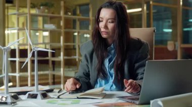 Ofis masasında çalışan Asyalı iş kadını mühendis. Yel değirmeni elektrik şirketi. Yorgun iş kadını.