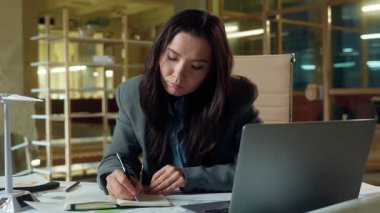 Asyalı mimar tasarımcı iş kadını ofis masasında çalışıyor. Yel değirmeni elektrik projesinde çalışıyor. Yorgun iş kadını Koreli Çinli kız çok çalışıyor.