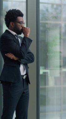 Dalgın Afrikalı Amerikalı iş adamı, kaygılarını dile getirdi. Pencereden bakıp çözüm arayışları kötü bir sorun yaratıyor. Etnik iş adamı çok çalışıyor.