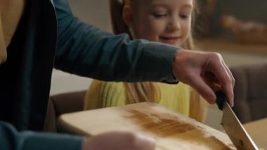 Mutfakta beyaz bir aile babası, küçük tatlı bir kız çocuğu, salata pişiriyor, malzemeleri bıçakla kesiyor, vitaminli sebzelerle konuşuyor sağlıklı beslenme tebessümleri ile konuşuyor.