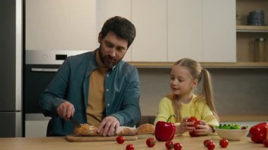 Mutfakta mutlu bir aile birlikte kahvaltı yapıyor. Kafkasyalı bir baba yemek pişiriyor. Ekmek kesiyor. Yüksek