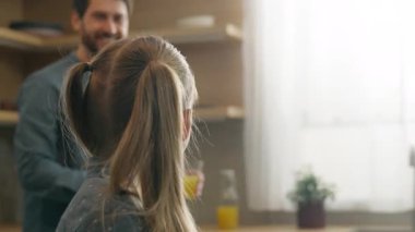 Kafkasyalı mutlu bir aile, mutfakta gülümsüyor. Küçük kız, kız, çocuk, evde şefkatli baba. İki bardak turuncu turunçgil, sağlıklı vitamin suyu getiriyor.