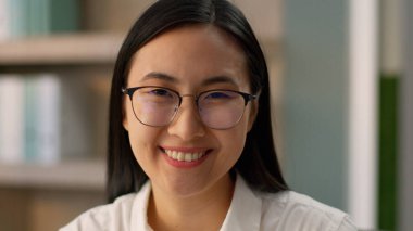 Yakın plan mutlu Asyalı Asyalı iş kadını kadın yönetici gülümseyen Çinli Koreli iş kadını kadın işçi sekreter işveren gözlüklü ofis kamerasına bakıyor.