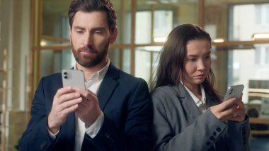 Çoklu etnik çeşitlilikte iş kadını cep telefonunu birlikte kullanıyor ofis chat uygulamasında çalışıyor Kafkasyalı iş adamı Koreli iş kadını internet gezen akıllı telefon cihazları kullanıyor