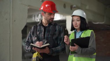 Çok ırklı müteahhitler iş görüşmesi kadın inşaat mühendisi Kafkasyalı ustabaşı sert adam Japon müfettişin tavsiyesini dinleyin güvenlik denetimi kontrol notları not listesi pano inşaatı