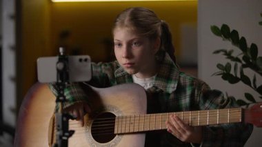 Yetenekli Kafkasyalı küçük kız akustik gitar çalmayı öğreniyor. İnternette telefon dersi veriyor. Öğrenci blogcu çocuk.