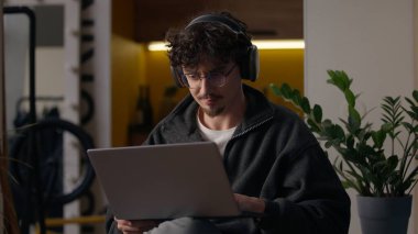 Ev adamı serbest programcısının bilgisayarında çalışan konsantre beyaz adam kulaklıkla web sitesi tasarımcısı ile sohbet ediyor sanal oyun oynayan bilgisayar erkeği kullanarak internet uygulama hipster geliştiricisi yazıyor.