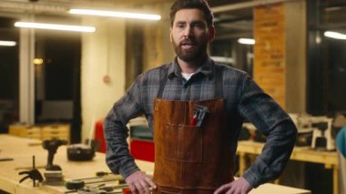 Neşeli beyaz adam ahşap ustası gülümseyip kalçalara poz veriyor. Atölye marangoz ustası, marangozluk işi sanatçısı. Kamera tamircisi, marangoz, marangoz, marangoz, marangoz.