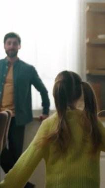 Mutfakta beyaz bir aile, mutlu bir ebeveyn, mutfakta mutlu bir baba, küçük bir çocuk, koşuyor, koşuyor, babasına koşuyor, faal bir baba, kalkıyor, dönüyor, evde dönüyor, sarılıyor, oyun oynuyor.