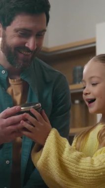 Mutfaktaki beyaz aile teslimat paketlerini boşaltıyor baba baba baba küçük kız çocuk mutlu kız ürünleri açıyor vitamin reçeli portakal suyu şişesi süt sebzeleri alıyor.