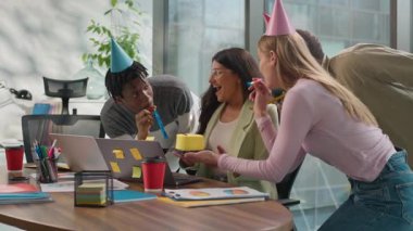 Ofiste dizüstü bilgisayarda çalışan Hintli iş kadını Arap kadın üç çok ırklı iş arkadaşı doğum günü pastası çeşitliliğini gayri resmi başlangıç işçileri hediyesiyle kutluyor.