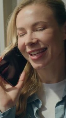 Cilveli, beyaz kadın müşteri telefonda konuşuyor. Pencereye bak. Güzel kadın iş kadını saçlarına dokunuyor.