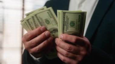 Kesilmiş manzara. Dolarları tutan erkek eli. Kafkasyalı, orta yaşlı iş adamı. Elinde para tutuyor.