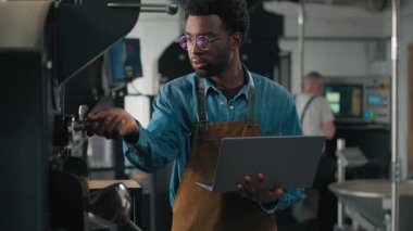 Kontrol kontrollerini denetleyen Afro-Amerikalı erkek adam kavrulmuş makine kokusundan bir şeyler alıyor kahve çekirdekleri kokusu tatmin oluyor online veri yazma işi küçük işletme yöneticiliği