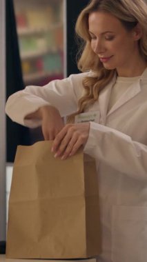 Eczane ilaç paketi kadın doktor ceket eczacı sağlık görevlisi ilaç sipariş hapları vitamin hapları kağıt torbada kadın beyaz kadın eczane asistanı