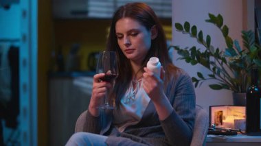 Zor bir seçim olduğunu düşünen üzgün bir kadın şarap ya da hap içer antibiyotik içen hasta bir kız hayal kırıklığına uğramış beyaz bir kız evde ağrı kesici içiyor.