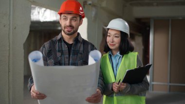 İki farklı Kafkasyalı Japon müteahhit erkek inşaat mühendisi kadın inşaat mühendisi mimar, miğfer üniformalı işçiler planlama projesini tartışıyorlar.