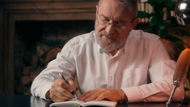 Kendinden emin, yaşlı, beyaz, olgun bir erkek kamera önünde el ele tutuşmuş ofis işadamı yakışıklı, yaşlı çalışan portresi liderinin içindeki iş adamına bakıyor.