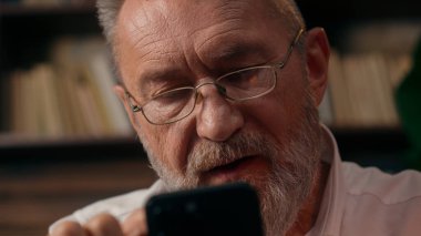 Kendinden emin, yaşlı, beyaz, olgun bir erkek kamera önünde el ele tutuşmuş ofis işadamı yakışıklı, yaşlı çalışan portresi liderinin içindeki iş adamına bakıyor.