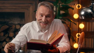 Kendinden emin, yaşlı, beyaz, olgun bir erkek kamera önünde el ele tutuşmuş ofis işadamı yakışıklı, yaşlı çalışan portresi liderinin içindeki iş adamına bakıyor.