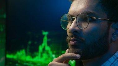 Gözlüklü Hintli Arap adam şifre çözücü kodcu bilişim uzmanı, erkek etnik adam iş programcısı, ticaret grafiği kripto para birimi neonu analiz etmeyi düşünüyor.