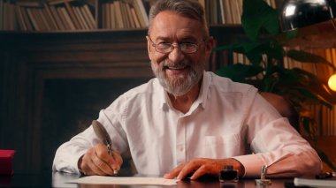 Kendinden emin, yaşlı, beyaz, olgun bir erkek kamera önünde el ele tutuşmuş ofis işadamı yakışıklı, yaşlı çalışan portresi liderinin içindeki iş adamına bakıyor.