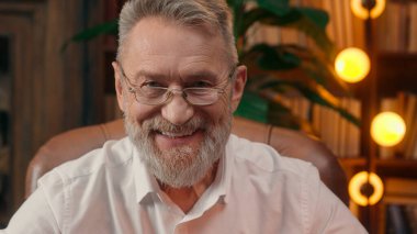 Kendinden emin, yaşlı, beyaz, olgun bir erkek kamera önünde el ele tutuşmuş ofis işadamı yakışıklı, yaşlı çalışan portresi liderinin içindeki iş adamına bakıyor.