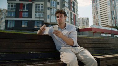 Kafası karışmış Kafası karışık beyaz adam cep telefonu kullanıyor. Akıllı telefon kullanıyor. Haber okuyan erkek öğrenci, kahve içiyor.