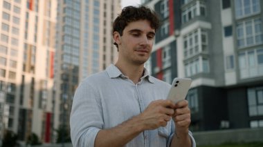 Kafkasyalı bir adam cep telefonuyla yürür sosyal medya teknolojisi ağları internet çalışanı, erkek işadamı, iş adamı şehir dışında cihaz saklayan cep telefonu işçisi.